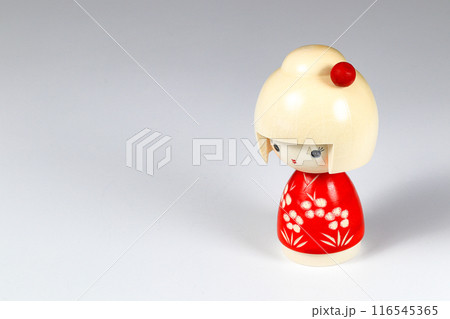 Japanese wooden dolls "kokeshi" in red Kimono suit, toy for a decoration, souvenir from Japan Isolated on white background. 116545365