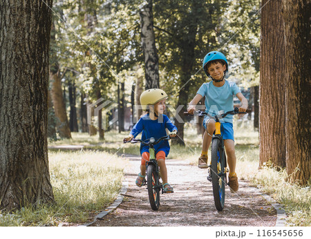 Happy children riding bicycles in city park on hot summer day 116545656