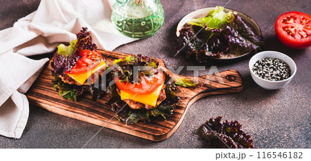 Keto burgers on lettuce leaves from cutlet, tomatoes and cheese on a board web banner 116546182