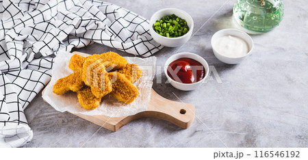 Crispy nuggets on paper on a board and sauce in a bowl on the table web banner Crispy nuggets on paper on a board and sauce in a bowl on the table web banner 116546192
