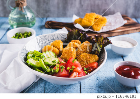 Bowl with crispy nuggets, tomato and cucumber on the table Bowl with crispy nuggets, tomato and cucumber on the table 116546193