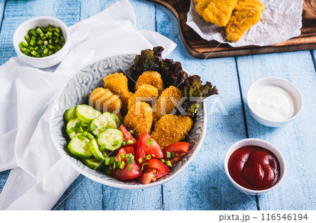 Fried chicken nuggets, cucumber and tomato in a bowl on the table Fried chicken nuggets, cucumber and tomato in a bowl on the table 116546194