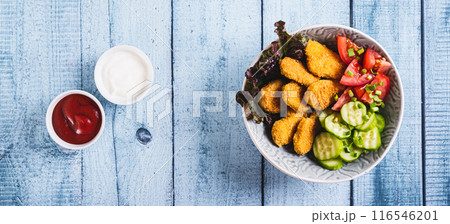 Fried chicken nuggets, cucumber and tomato in a bowl on the table top view web banner Fried chicken nuggets, cucumber and tomato in a bowl on the table top view web banner 116546201