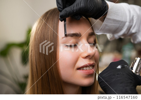 Eyebrow artist performs brow correctionon client, Eyebrow artist performs brow correctionon client, 116547160