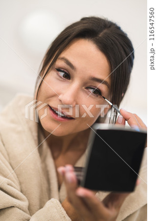 Pretty young woman looking in the mirror and making her eyes Pretty young woman looking in the mirror and making her eyes 116547560