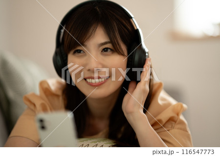 ソファに寝転んでスマホ音楽を聴くミドルの女性 ソファに寝転んでスマホ音楽を聴くミドルの女性 116547773