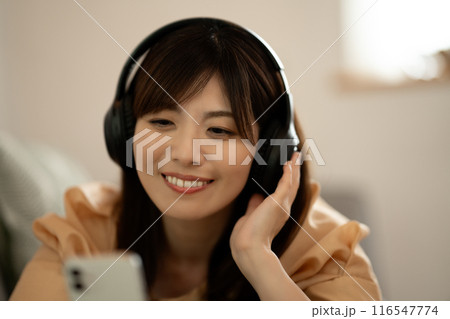 ソファに寝転んでスマホ音楽を聴くミドルの女性 ソファに寝転んでスマホ音楽を聴くミドルの女性 116547774