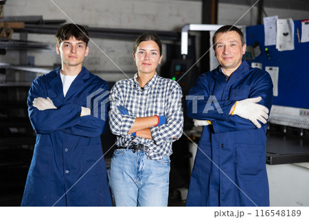Group of smiling workers posing together in metalworking workshop 116548189