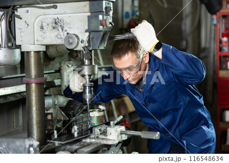 Skilled operator working on drilling machine in metalworking shop Skilled operator working on drilling machine in metalworking shop 116548634