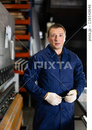 Experienced middle-aged worker posing in professional metalworking workshop 116548646