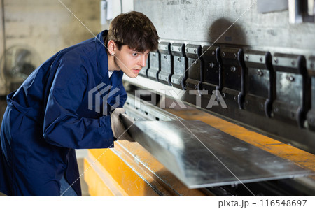 Young worker works on sheet bending machine at metallurgical plant Young worker works on sheet bending machine at metallurgical plant 116548697