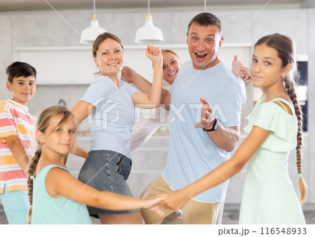Children stand around their dancing parents in kitchen. Children stand around their dancing parents in kitchen. 116548933
