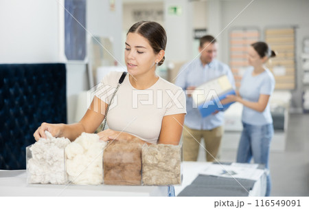 Young girl choosing filler for sofa or pillows in furniture store 116549091