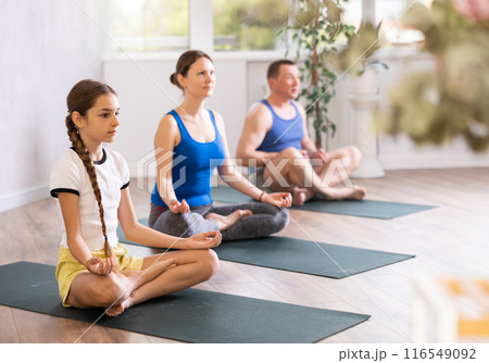 Pre-teen girl performing yoga exercises with brother and parents at gym, family health concept Pre-teen girl performing yoga exercises with brother and parents at gym, family health concept 116549092