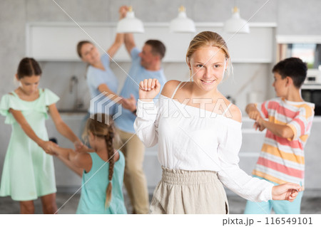 Behind cheerful girl, big family of parents, sisters, brother is rejoicing, dancing, having fun. 116549101