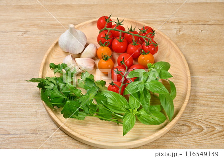 イタリアン料理用のハーブと野菜の食材イメージ。ミニトマト、イタリアンパセリ、バジル、にんにく。 116549139