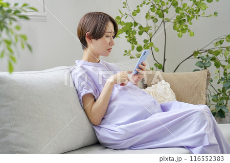自宅で悩みながらスマートフォンを使う高齢妊娠をした妊婦 自宅で悩みながらスマートフォンを使う高齢妊娠をした妊婦 116552383