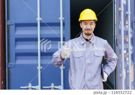 Asian male logistic worker in safety workwear portrait at the container yard. Logistic foreman portrait. Asian male logistic worker in safety workwear portrait at the container yard. Logistic foreman portrait. 116552722