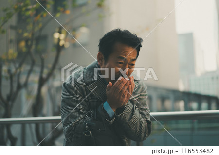 寒さで手に息を吹きかける50代サラリーマン 116553482