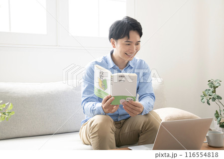 ソファーに座って投資の本を読む男性 ソファーに座って投資の本を読む男性 116554818