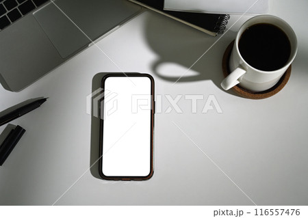 Smartphone with empty screen, coffee cup and laptop on white table. Top view, Flat lay Smartphone with empty screen, coffee cup and laptop on white table. Top view, Flat lay 116557476