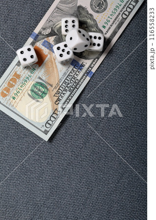 White dice with black markings. They lie on a surface covered with a coarse gray cloth. Under them lies a hundred dollar bill. White dice with black markings. They lie on a surface covered with a coarse gray cloth. Under them lies a hundred dollar bill. 116558233