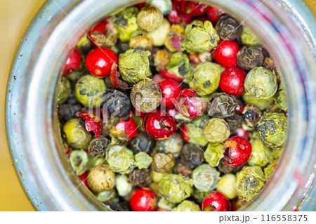 Vibrant mix of red, green, and black peppercorns inside a jar. 116558375