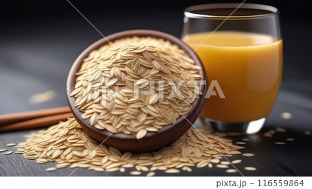 A glass of oat milk and oat flakes on a dark wooden table. 116559864
