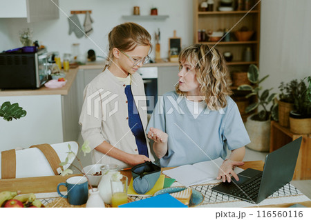 Caucasian nurse mother and daughter discussing school project during breakfast time before work Caucasian nurse mother and daughter discussing school project during breakfast time before work 116560116