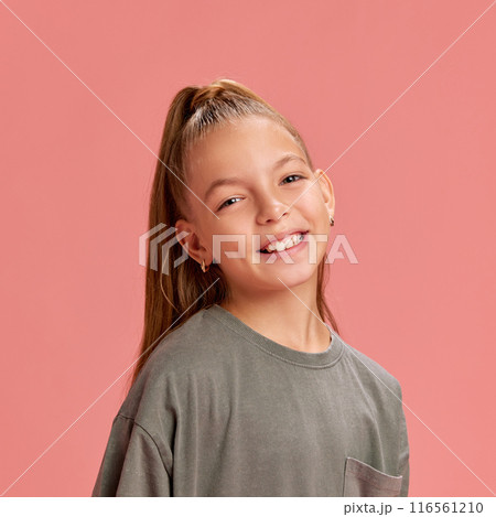 Portrait of attracting young girl, 9 years old child posing with smile, in casual t-shirt and ponytail against peach background Portrait of attracting young girl, 9 years old child posing with smile, in casual t-shirt and ponytail against peach background 116561210