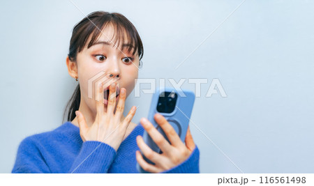 スマホを見て驚いた表情の女性 116561498