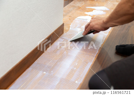 中古住宅のリフォームで廊下の床にフロアタイルを貼るクロス職人 116561721