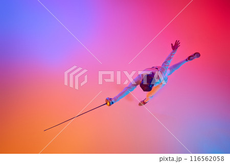 Nature of sport. View from above, fencer lunges with precision, his epee extended in mixed neon lights against gradient studio background. 116562058