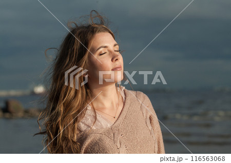 Carefree young adult female model with windy brown hair walking outdoor Carefree young adult female model with windy brown hair walking outdoor 116563068