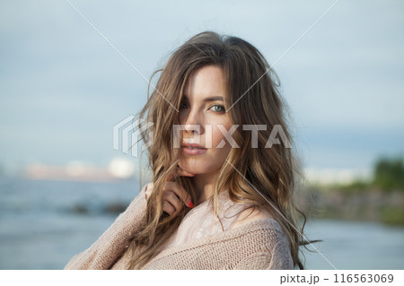 Glamorous young adult female model with windy brown hair walking outdoor 116563069