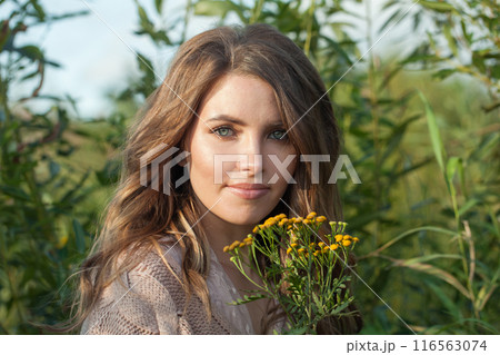 Happy young adult female model with windy brown hair walking outdoor 116563074