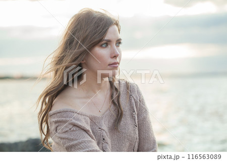 Beautiful face of young adult female model with windy brown hair walking outdoor 116563089