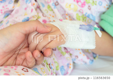 Mother holding child hand with saline IV solution in hospital Mother holding child hand with saline IV solution in hospital 116563650
