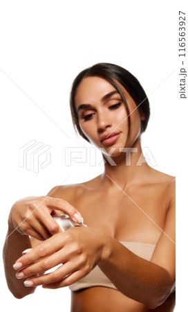 Focus on female hands, woman applying hand moisturizing cream isolated on white background. Model with tanned body 116563927