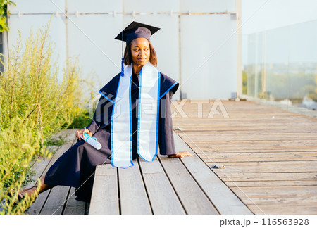 A graduate of bachelor of science. Portrait of female student in cap and gown graduation costume, holding diploma Study, education, university, college, graduate concept. 116563928