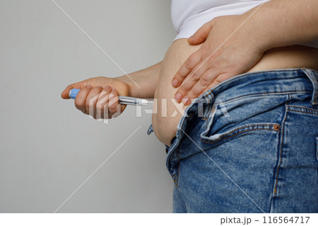 Woman is making insulin injection in the stomach 116564717