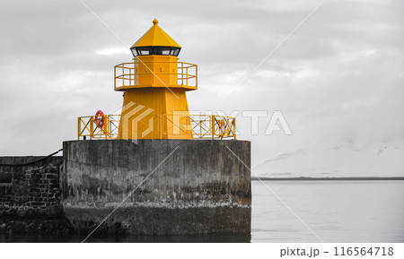 Yellow lighthouse tower stands at the concrete breakwater. Iceland 116564718