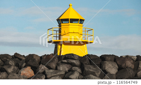 Yellow lighthouse tower standing at the breakwater. Iceland 116564749