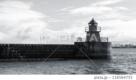 Lighthouse tower standing on a concrete breakwater, monochrome Lighthouse tower standing on a concrete breakwater, monochrome 116564755