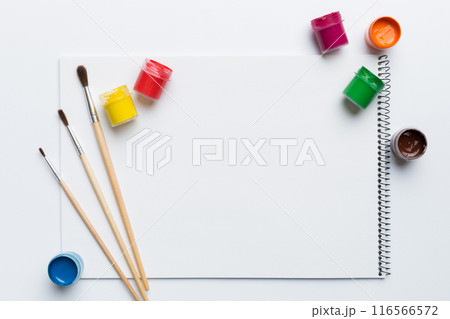 Album pages and paints, pencils, brush on a colored background. Top view with empty space. workplace for creativity. home teaching concept drawing 116566572