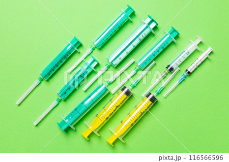 Top view of medical syringes with needles at green background with copy space. Injection treatment concept Top view of medical syringes with needles at green background with copy space. Injection treatment concept 116566596