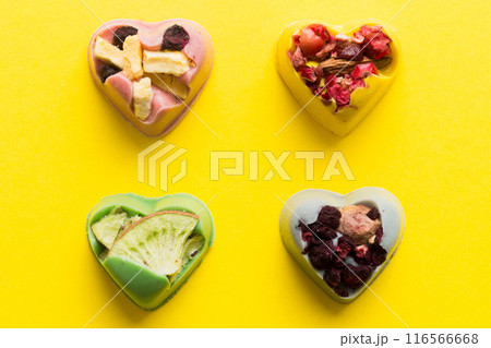 chocolate sweets in the form of a heart with fruits and nuts on a colored background. top view with space for text, holiday concept chocolate sweets in the form of a heart with fruits and nuts on a colored background. top view with space for text, holiday concept 116566668