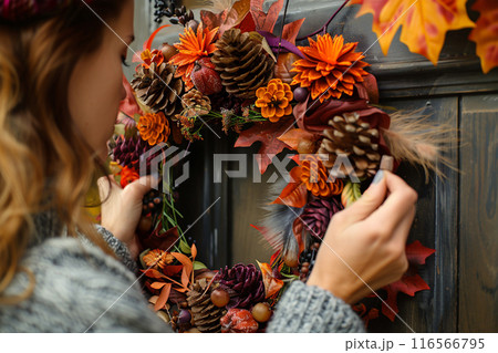 Woman decorate door with autumn wreath Woman decorate door with autumn wreath 116566795