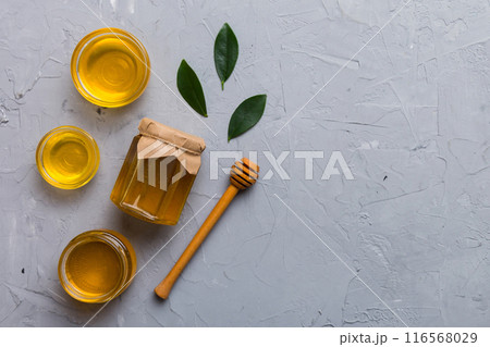 Honey jar with wooden honey dipper on white background top view with copy space. Delicious honey bottle Honey jar with wooden honey dipper on white background top view with copy space. Delicious honey bottle 116568029