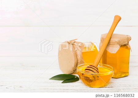 Honey in jar with leaves and honey dipper on colored background top view with copy text Honey in jar with leaves and honey dipper on colored background top view with copy text 116568032
